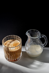 Image showing coffee in glass and jug of milk or cream on table