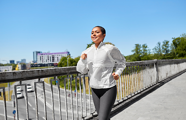 Image showing african american woman running along bridge