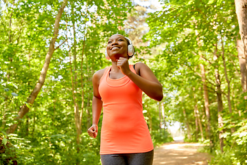 Image showing happy african woman in headphones running in park