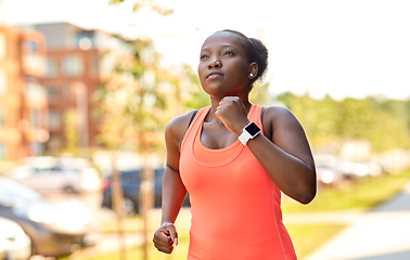 Image showing african woman with smart watch running in city