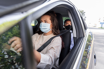 Image showing female driver in mask driving car with passenger