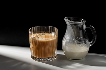 Image showing coffee in glass and jug of milk or cream on table