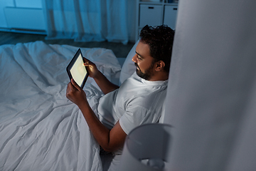 Image showing indian man with tablet pc in bed at home at night