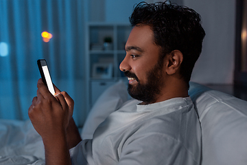 Image showing indian man with smartphone in bed at home at night