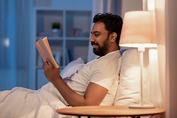 Image showing happy indian man reading book in bed at night