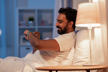 Image showing indian man with health tracker in bed at night