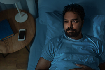 Image showing speelpess indian man lying in bed at night