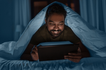 Image showing indian man with tablet pc in bed at home at night