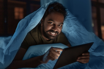 Image showing indian man with tablet pc in bed at home at night