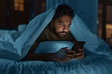 Image showing indian man with smartphone in bed at home at night