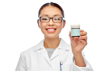 Image showing smiling female doctor holding jar of medicine