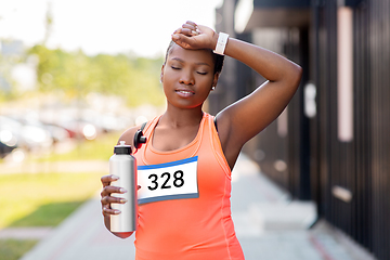 Image showing tired female marathon runner with bottle of water