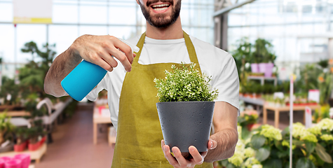 Image showing happy gardener or farmer with sprayer and flower