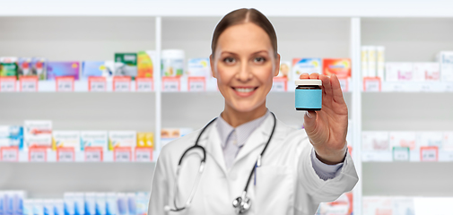 Image showing smiling female doctor with medicine at pharmacy