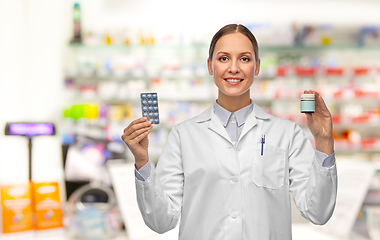 Image showing smiling female doctor holding medicine at pharmacy