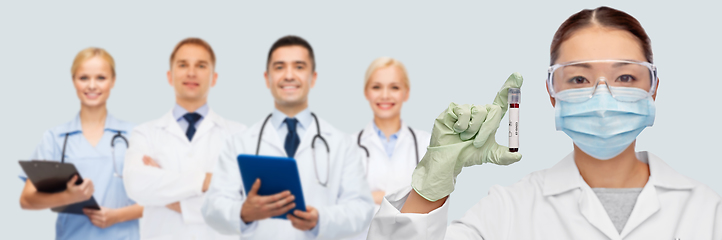 Image showing asian female doctor holding beaker with blood test