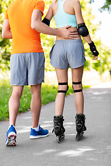 Image showing happy couple with roller skates riding outdoors