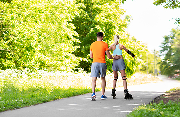 Image showing happy couple with roller skates riding outdoors