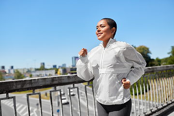 Image showing african american woman running along bridge