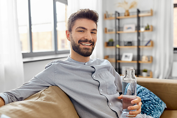 Image showing happy man drinking water from glass bottle at home