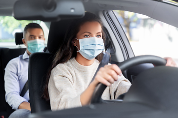 Image showing female driver in mask driving car with passenger