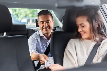 Image showing female car driver taking money from passenger