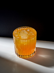 Image showing glass of orange juice with ice on table