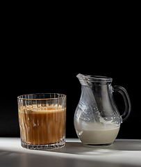 Image showing coffee in glass and jug of milk or cream on table