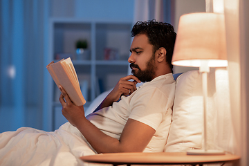 Image showing indian man reading book in bed at night