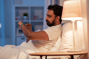 Image showing indian man with health tracker in bed at night