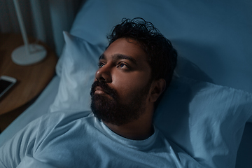 Image showing speelpess indian man lying in bed at night