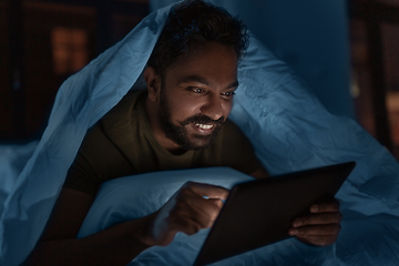 Image showing indian man with tablet pc in bed at home at night