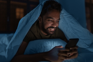 Image showing indian man with smartphone in bed at home at night