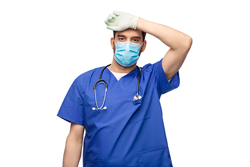 Image showing tired male doctor in blue uniform, mask and gloves