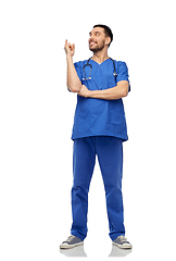 Image showing smiling doctor or male nurse pointing finger up