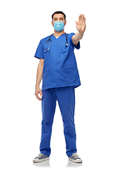 Image showing male doctor in blue uniform and mask showing stop