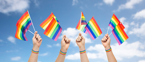 Image showing hands with gay pride rainbow flags and wristband