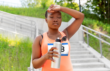 Image showing tired female marathon runner with bottle of water