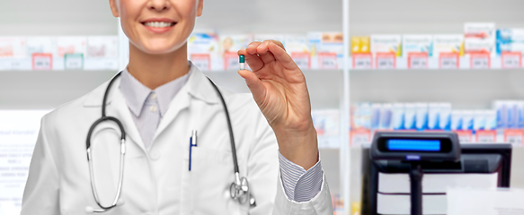 Image showing smiling female doctor showing medicine at pharmacy