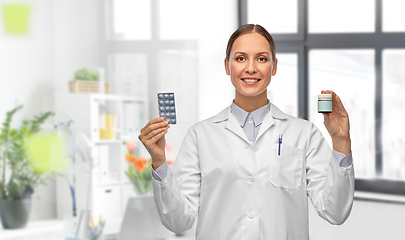 Image showing smiling female doctor holding medicine at hospital