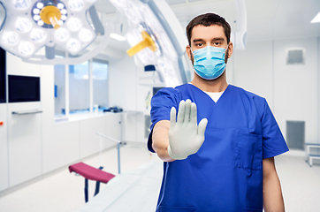 Image showing male doctor in blue uniform and mask showing stop