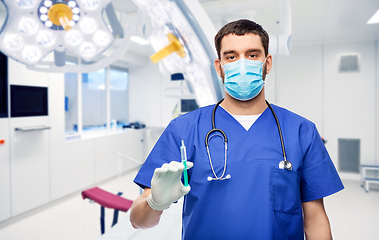 Image showing male doctor in mask and gloves with syringe