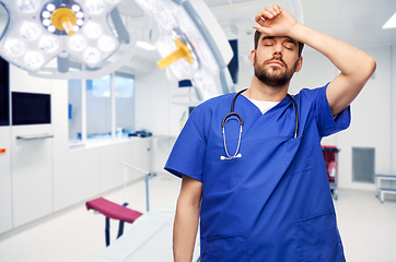 Image showing tired doctor or male nurse at surgery in hospital