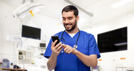 Image showing smiling doctor or male nurse using smartphone