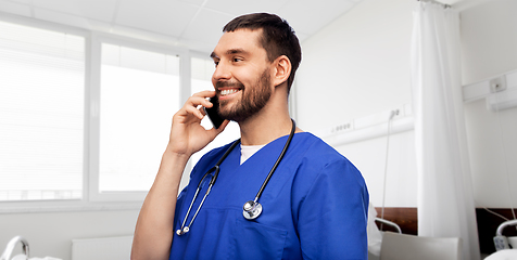 Image showing smiling doctor or male nurse calling on smartphone