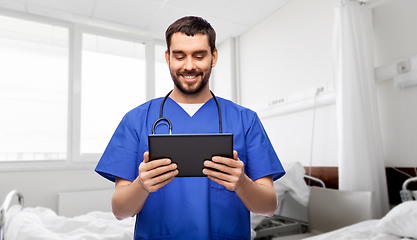 Image showing smiling doctor or male nurse using tablet computer