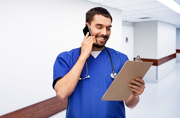 Image showing smiling doctor or male nurse calling on smartphone