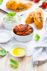 Image showing Sun dried tomato with olive oil as antipasto with avocado spread and baguette