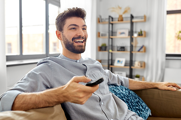 Image showing happy man with remote control watching tv at home