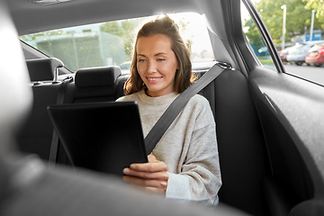 Image showing happy smiling woman in car using tablet computer